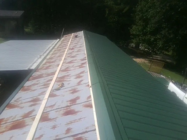Old rusted panels beside newly installed green metal roofing — Wind Damage Roof Repair by Roofing Brothers in Norcross