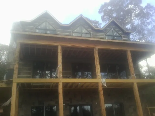 Dormers and porch framing on a large log home under construction — Roof Coating work by our crew in Norcross