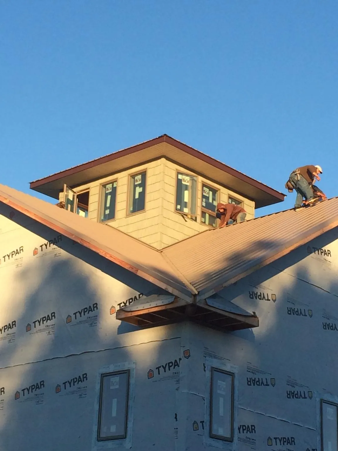 Roofers working around a rooftop cupola on a new metal roof at sunset — Roof Waterproofing in Norcross by Roofing Brothers